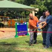 3 men cutting a ribbon for the new park opening