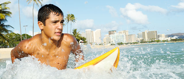 Teenager surfing off tropical coast.