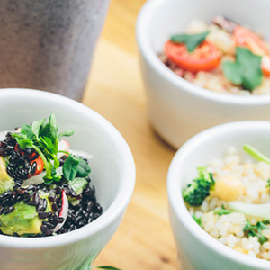 Bowls of grains and vegetables with glasses of smoothies