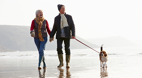 Couple walking dog at beach in the winter