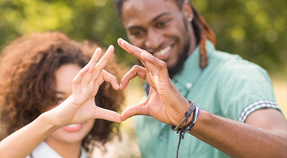 African American couple making heart shape with hands together