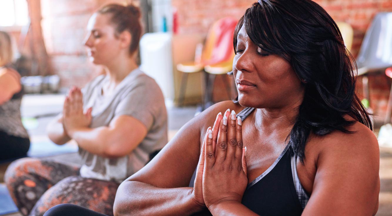 A woman meditates in a group exercise class.