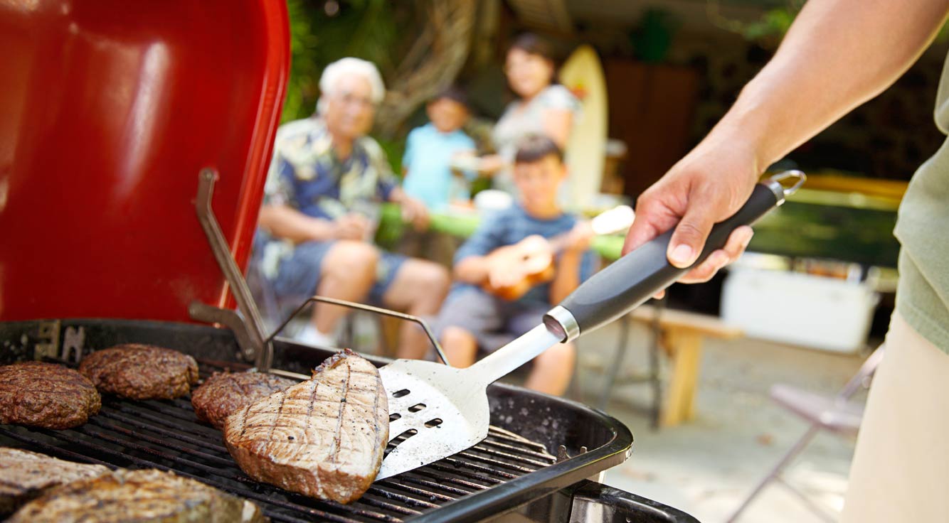 A spatula flips meat on a grill.