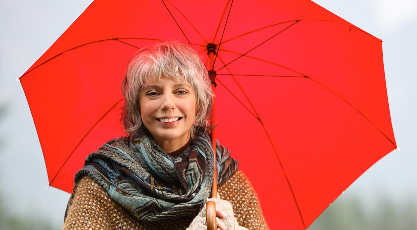 A woman strolls in the rain with a red umbrella