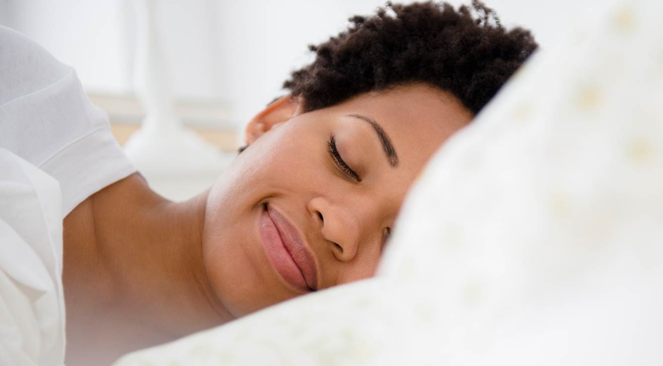A woman sleeps peacefully in a comfy bed.