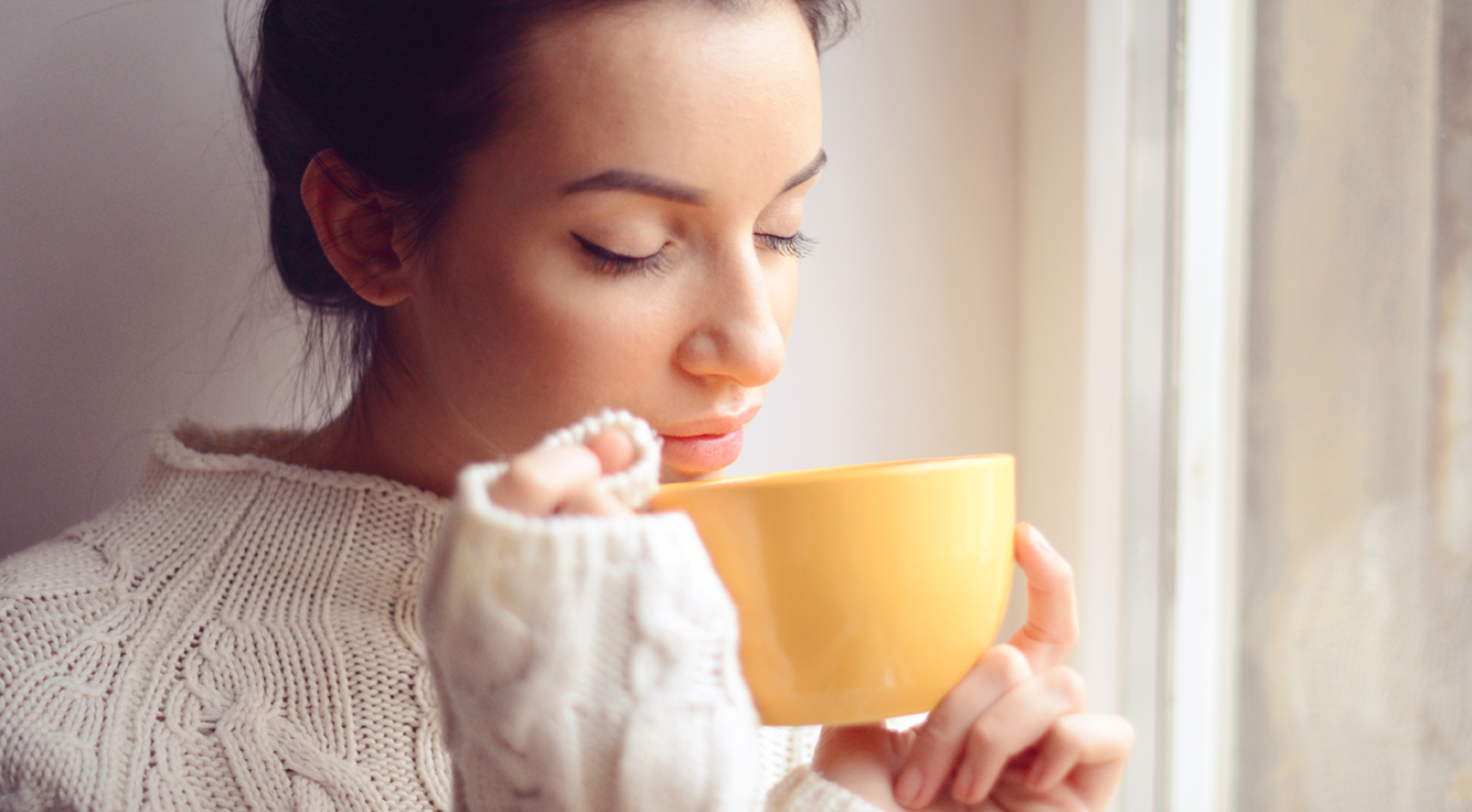 A young woman sips a cup of tea.