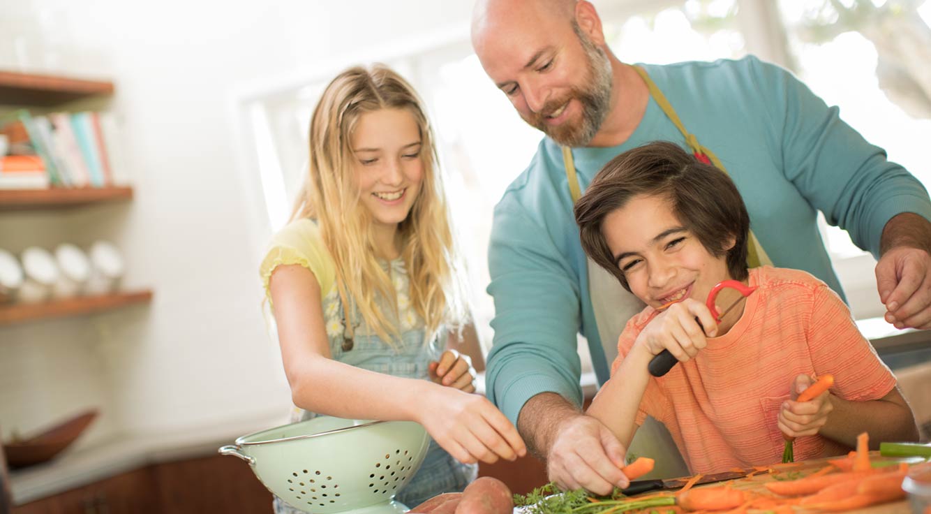 A father and his two children enjoy cooking dinner together.