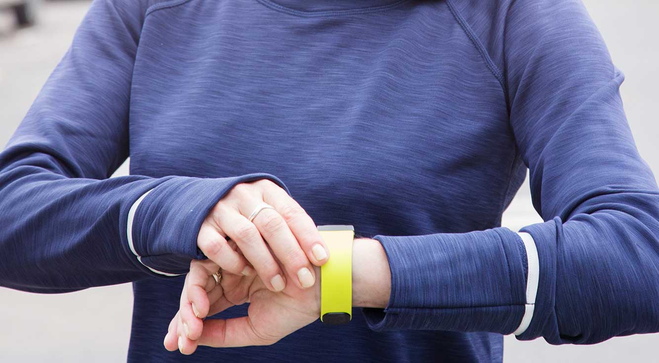 A woman in running gear checks the digital step-counter on her wrist
