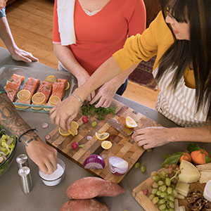 Three adults make a healthy meal together in the kitchen.