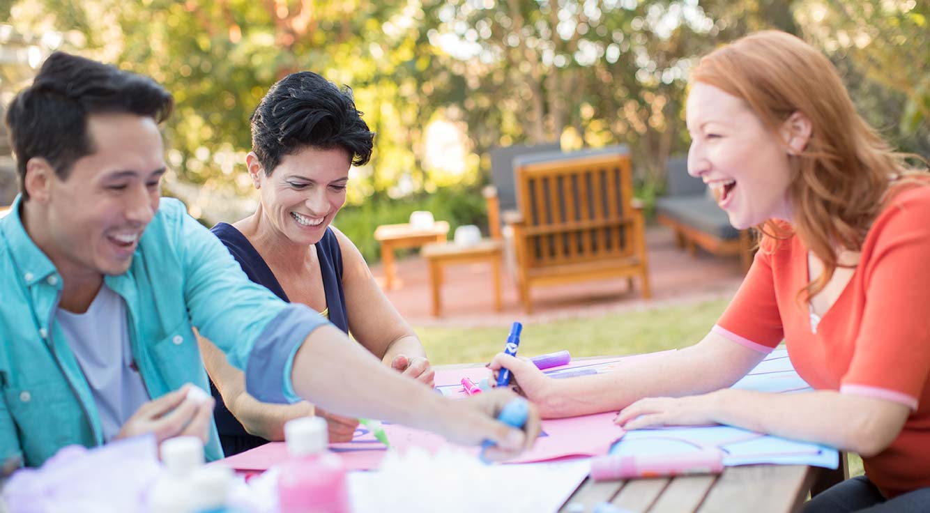 A smiling woman enjoys craft time with two friends.
