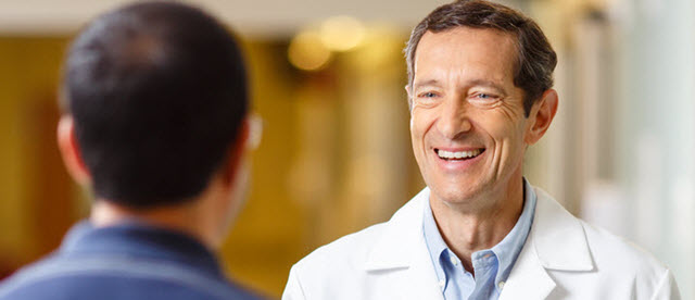 Doctor smiling and greeting patient in hospital hallway