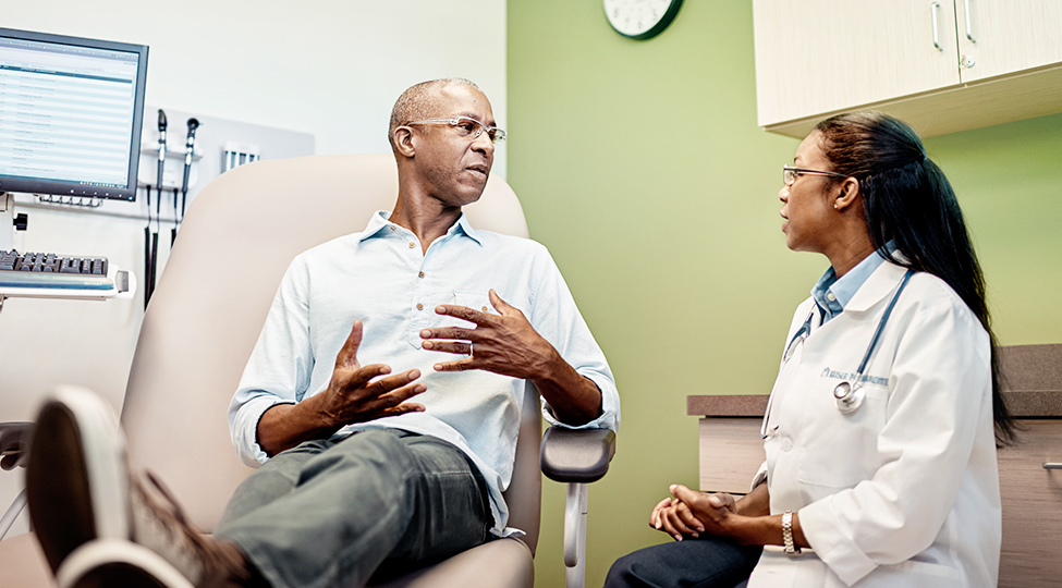 Patient discussing concerns with his doctor in medical office.