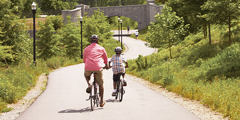 Father and son riding bicycles along scenic bike path.
