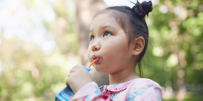 Young girl sipping from a juice box.